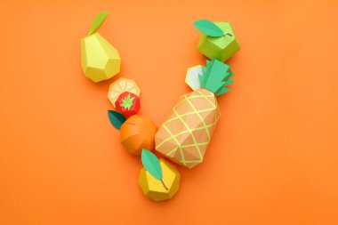 Kağıt meyvelerden V harfi, turuncu arka planda kağıttan yapılmış egzotik meyveler. Vitamin kavramı
