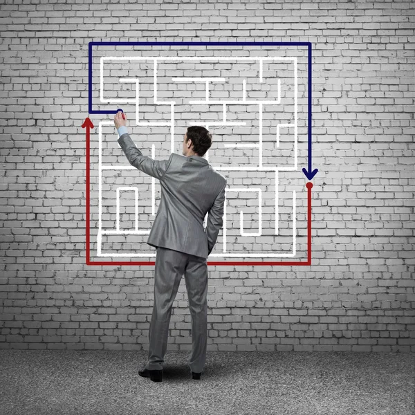 Businessman drawing labyrinth on wall — Stock Photo, Image