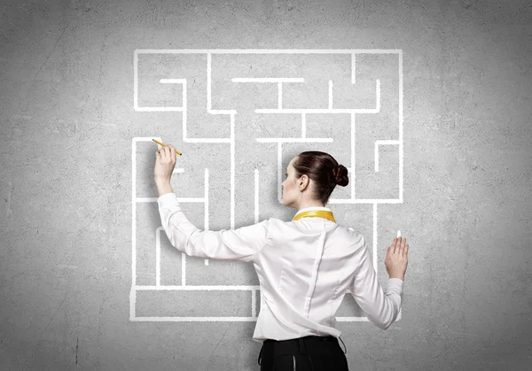 Businesswoman drawing labyrinth on wall — Stock Photo, Image