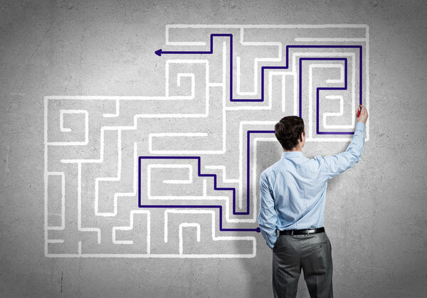 businessman drawing labyrinth on wall