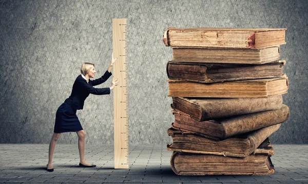Женщина измеряет груду старых книг — стоковое фото