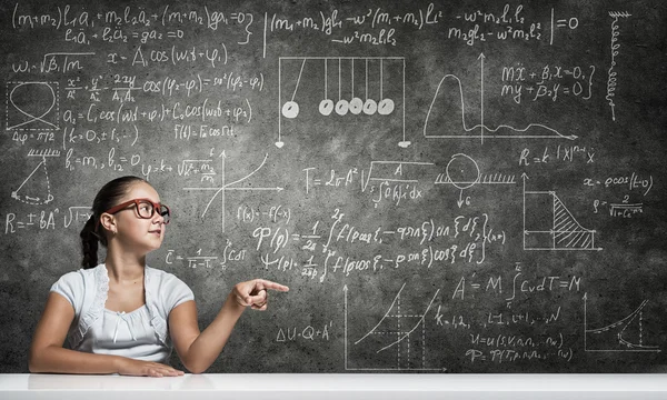 School meisje wijzen met de vinger naar blackboard — Stockfoto