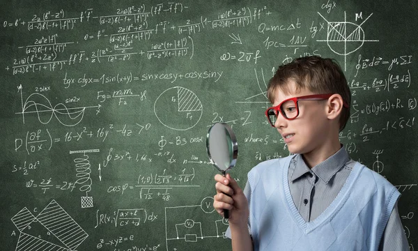 Cute boy looking through magnifying glass — Stock Photo, Image