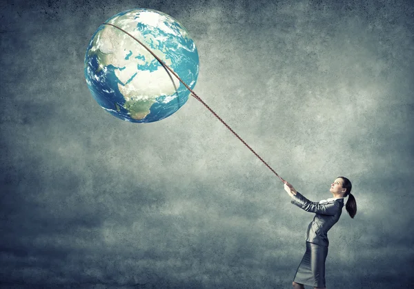 Businesswoman controlling planet with lead — Stock Photo, Image