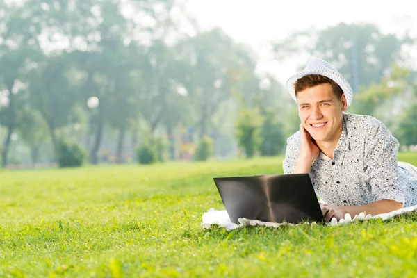 Jovem no parque com laptop — Fotografia de Stock