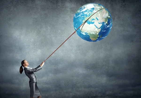 Businesswoman controlling planet with lead — Stock Photo, Image