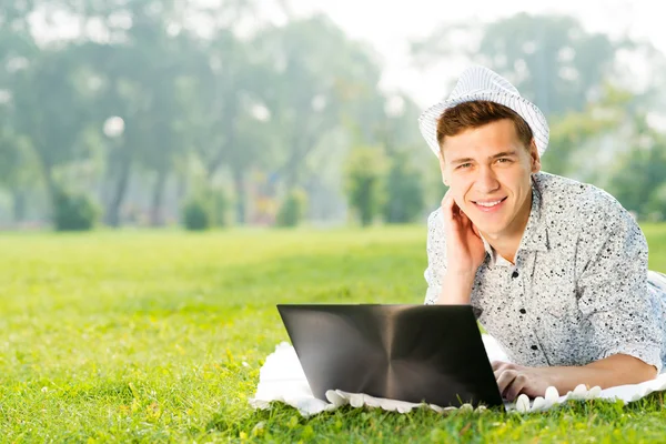 Νεαρός άνδρας στο πάρκο με φορητό υπολογιστή — Φωτογραφία Αρχείου