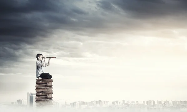 Kind auf Bücherstapel schaut in Spiegelglas — Stockfoto