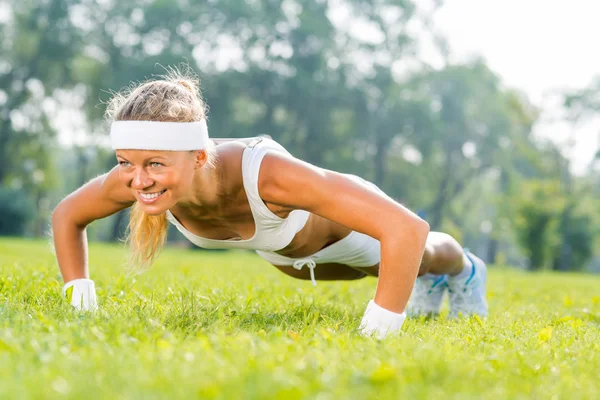 Kobieta robi push up w parku — Zdjęcie stockowe