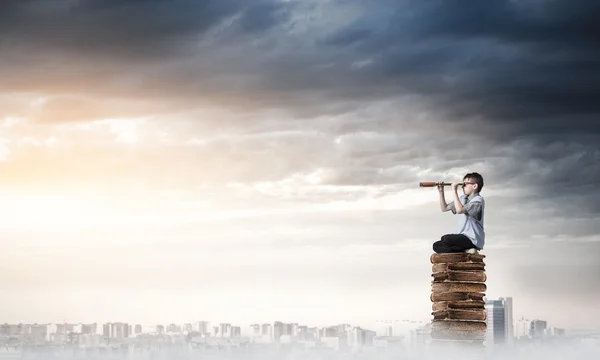 Kind auf Bücherstapel schaut in Spiegelglas — Stockfoto