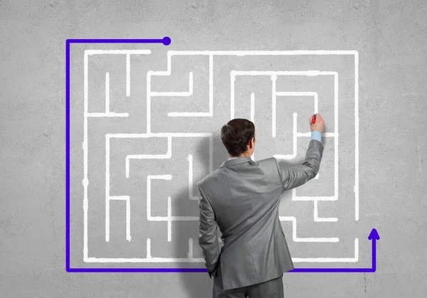 Businessman drawing labyrinth on wall — Stock Photo, Image