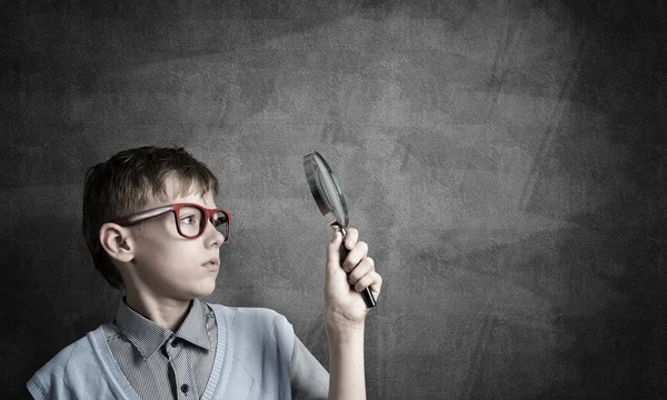 Netter Junge, der durch Vergrößerungsglas schaut — Stockfoto