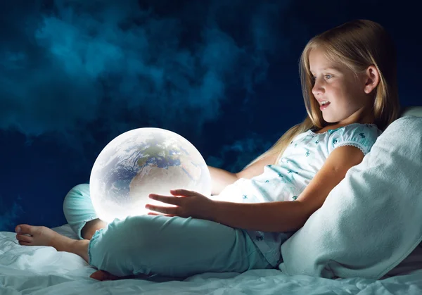Dziewczyna w łóżku i świecący glob — Zdjęcie stockowe