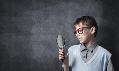 Meraklı okullu çocuk büyüteç ile