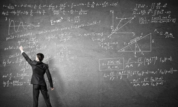 Teacher writing formulas on blackboard — Stock Photo, Image