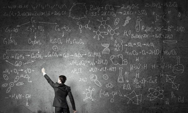 Scientist writing formulas on chalkboard — Stock Photo, Image