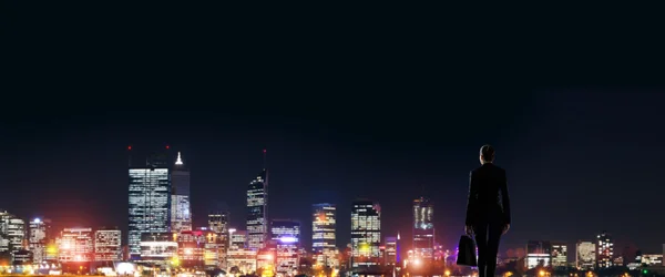 Zakenvrouw kijken naar nacht gloeiende stad — Stockfoto
