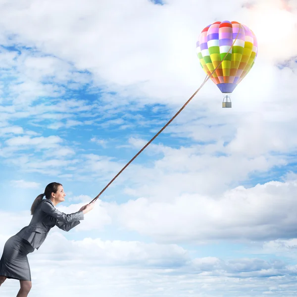 Young businesswoman pulling aerostat — Stock fotografie