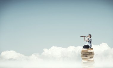Yığın kitap üzerinde oturan çocuk