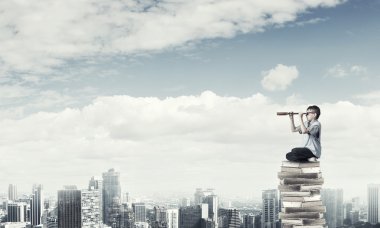 Yığın kitap üzerinde oturan çocuk