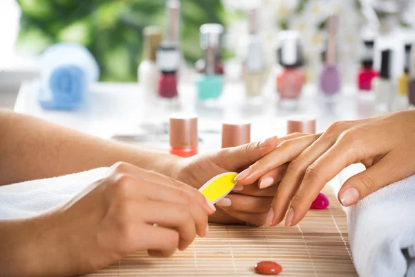 Woman in salon receiving manicure