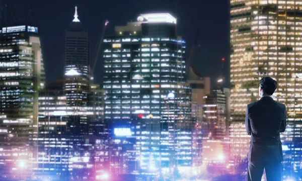 Бизнесмен смотрит ночной светящийся город — стоковое фото