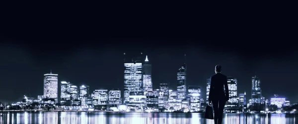 Empresária olhando para a noite brilhando cidade — Fotografia de Stock