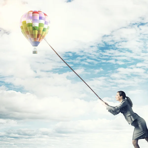 Young businesswoman pulling aerostat — Stock Photo, Image