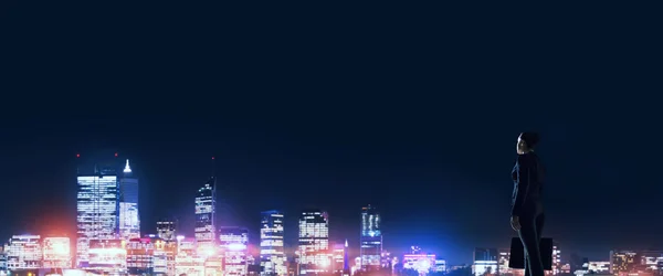 Бізнес-леді дивиться на нічне сяюче місто — стокове фото