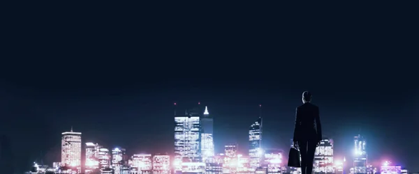 Бізнес-леді дивиться на нічне сяюче місто — стокове фото