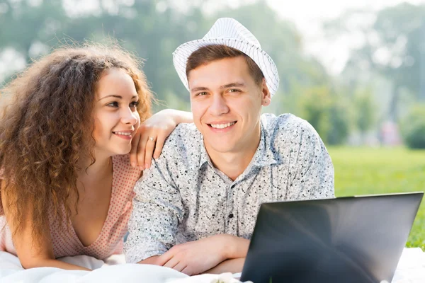 Pareja acostada junto con el ordenador portátil — Foto de Stock