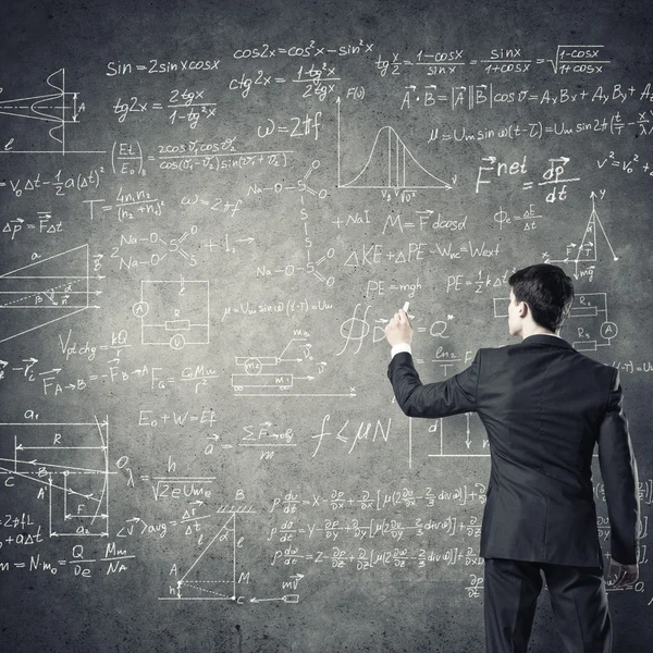 Man drawing formulas on chalkboard — Stock Photo, Image