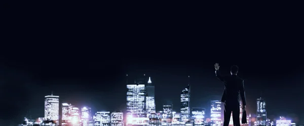 Бизнесмен смотрит ночной светящийся город — стоковое фото