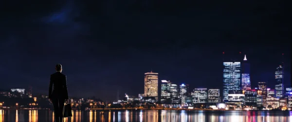 Ділова жінка дивиться нічне сяюче місто — стокове фото