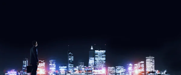 Бізнесмен дивиться нічне сяюче місто — стокове фото