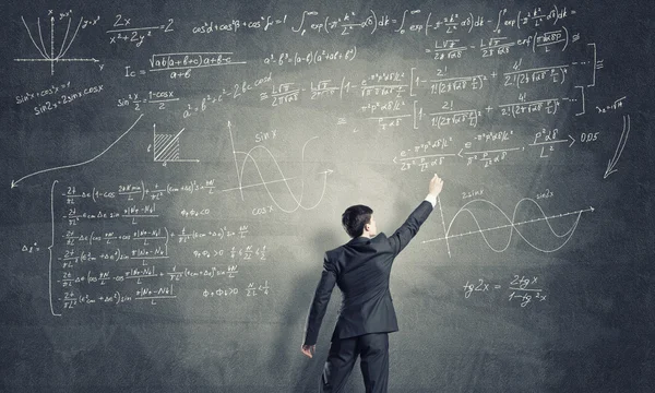 Man drawing formulas on chalkboard — Stock fotografie