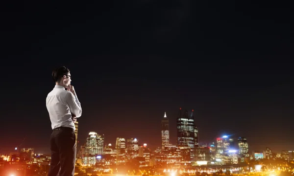 Zakenman die nacht gloeiende city bekeken — Stockfoto