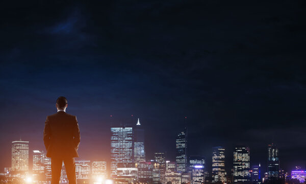 Businessman viewing night glowing city