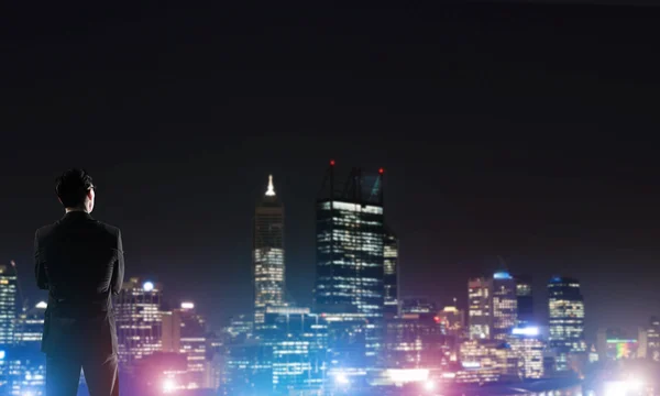 Zakenman die nacht gloeiende city bekeken — Stockfoto