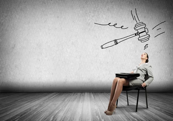 Young businesswoman sitting under drawn hammer — Stock Photo, Image