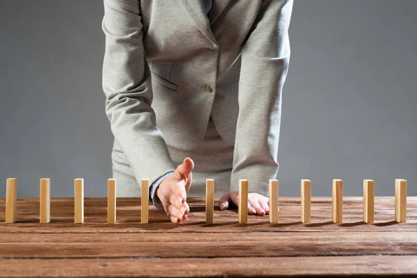 Businesswoman protecting dominoes from falling — Stock Photo, Image