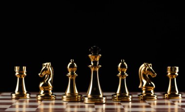 Satranç tahtasında duran altın satranç figürleri
