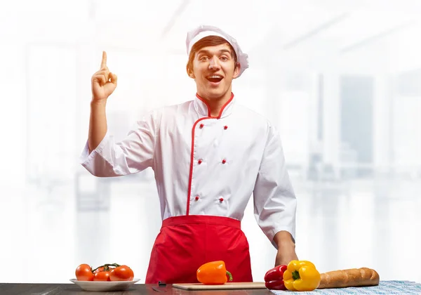 Joven chef masculino de pie cerca de la mesa de cocina —  Fotos de Stock