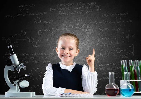 Маленькая девочка-ученый сидит за столом — стоковое фото