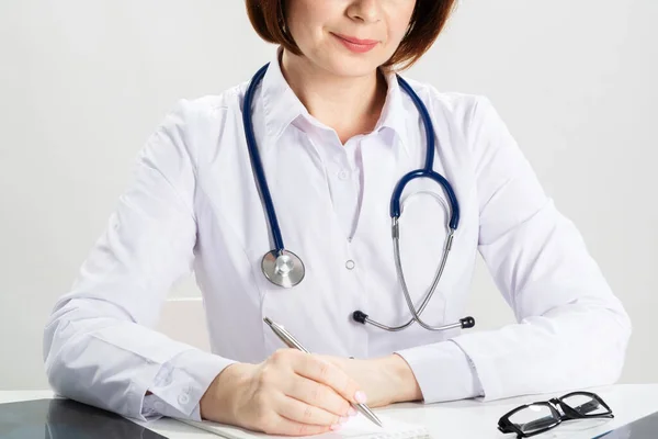 Закройте руки женщины-врача, пишущей на бумаге — стоковое фото