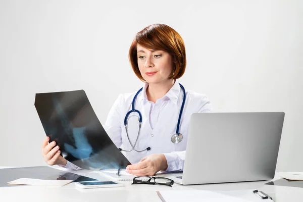 Hermoso médico mirando la radiografía en el consultorio — Foto de Stock