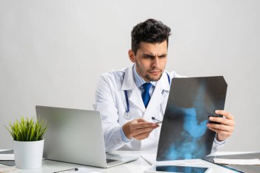 Yakışıklı genç doktor röntgen taramasına bakıyor.