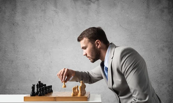 Businessman moving chess figure in chessboard — Stock Photo, Image
