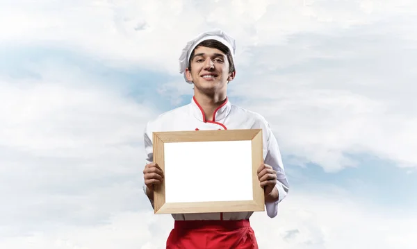 Young male chef holding blank white board — Stock Photo, Image