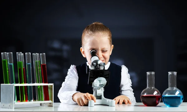 Malý vědec se dívá skrz mikroskop — Stock fotografie